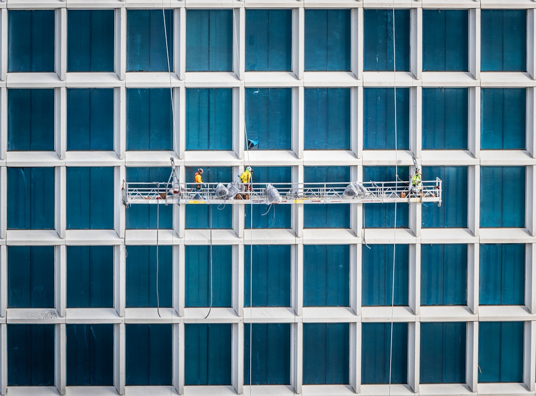 heros-img Construction workers hang from the side of a newly constructed building.